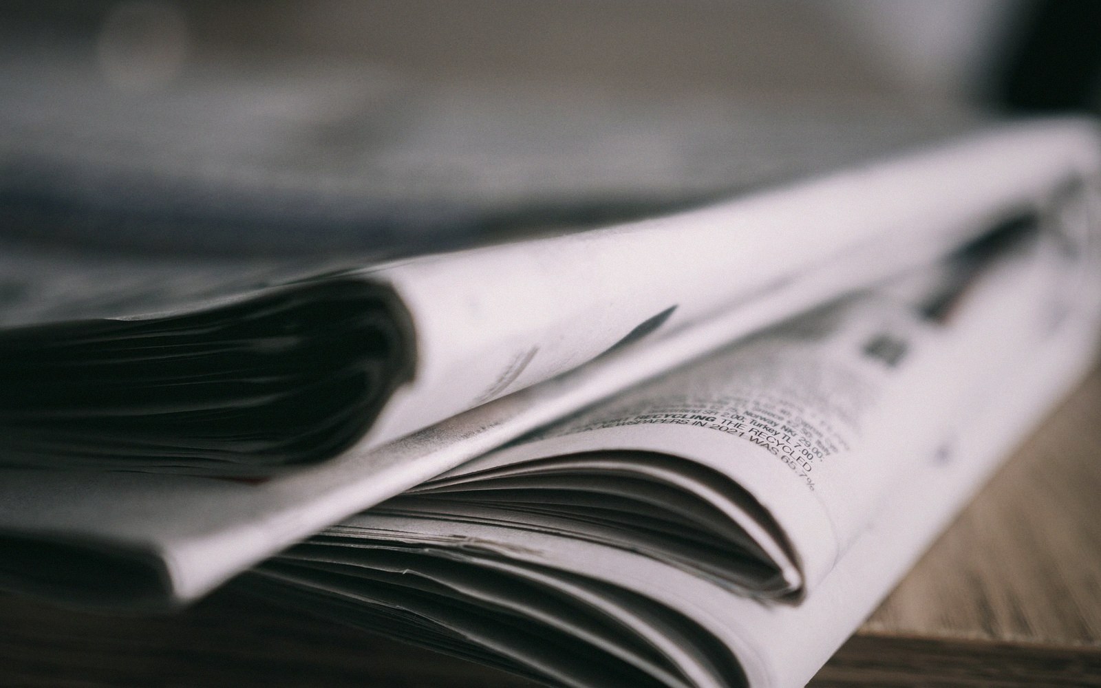 A folded stack of newspaper pages resting on a wooden surface